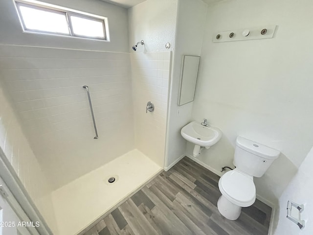 bathroom featuring wood-type flooring, toilet, sink, and a shower