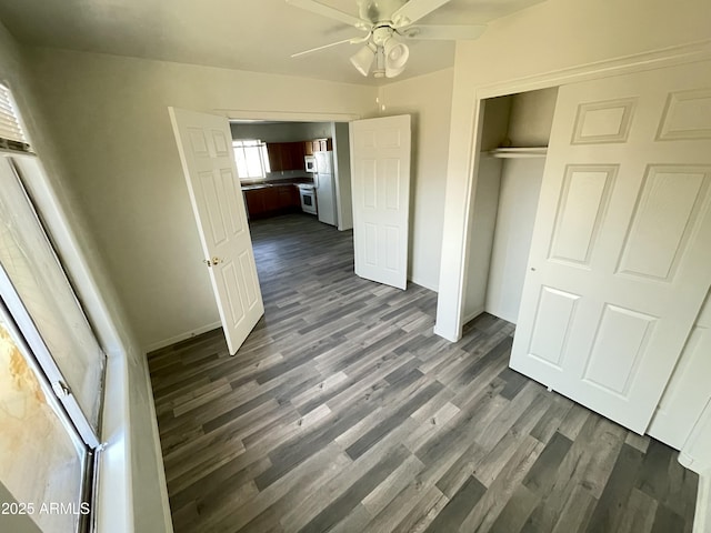 unfurnished bedroom featuring dark hardwood / wood-style flooring, white fridge, ceiling fan, and a closet