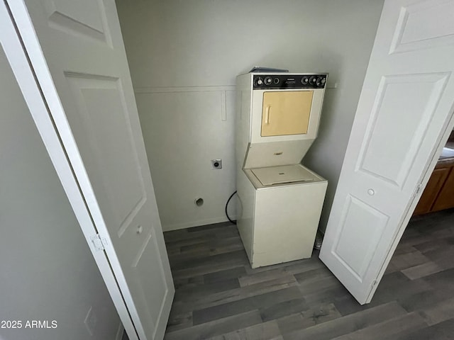 washroom featuring stacked washer / drying machine and dark wood-type flooring