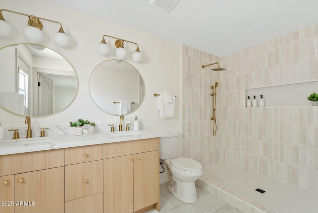 full bath featuring visible vents, toilet, a tile shower, and a sink