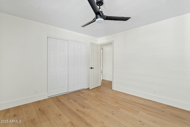 unfurnished bedroom with light wood finished floors, a closet, a ceiling fan, and baseboards