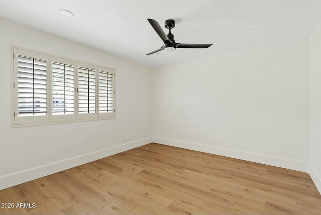 empty room with wood finished floors, a ceiling fan, and baseboards