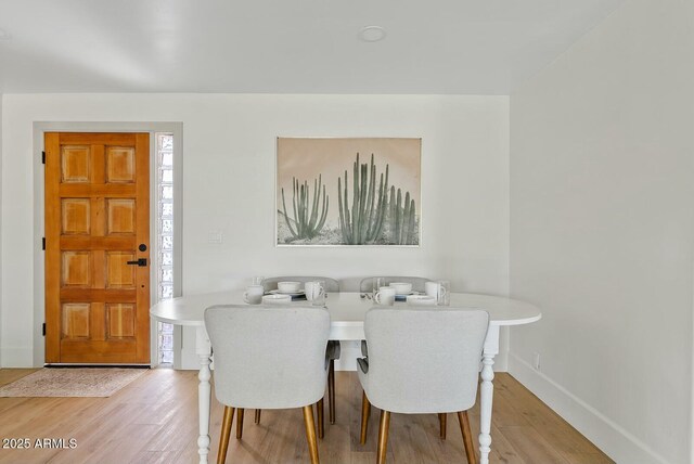 dining space featuring baseboards and light wood-style floors