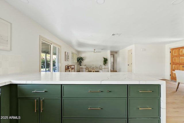 kitchen with light wood finished floors, green cabinets, open floor plan, and visible vents