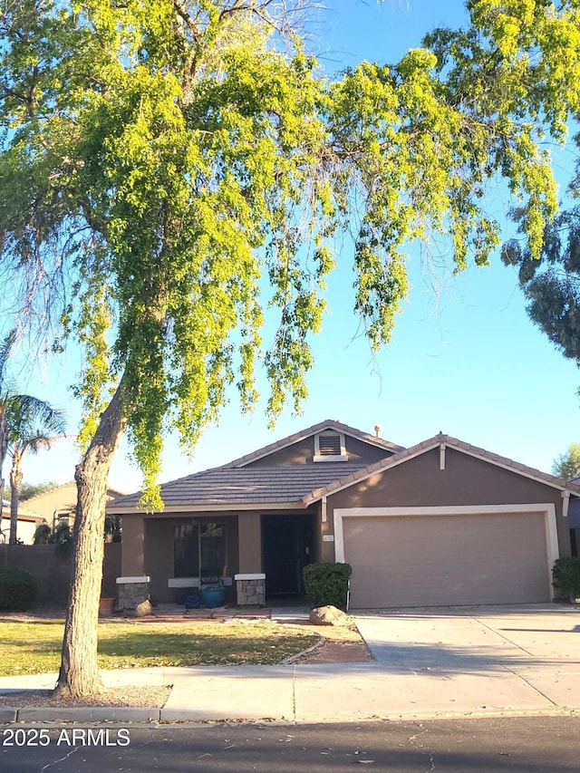 17257 W Papago St, Goodyear, AZ 85338 - single story home featuring stucco siding, a garage, concrete driveway, stone siding, and a tiled roof