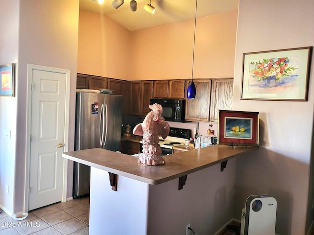 17257 W Papago St, Goodyear, AZ 85338 - kitchen with black microwave, freestanding refrigerator, electric range, a peninsula, and a breakfast bar