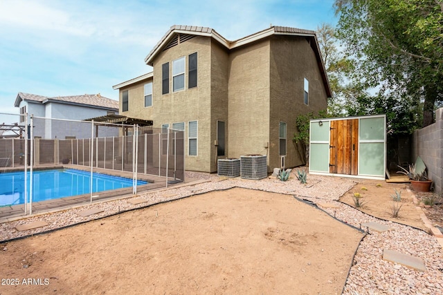 rear view of house with central AC, a fenced in pool, and a shed