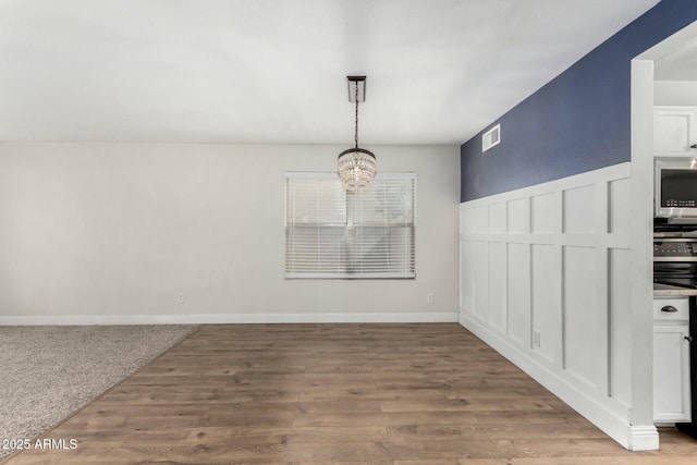 unfurnished dining area featuring hardwood / wood-style flooring and a chandelier