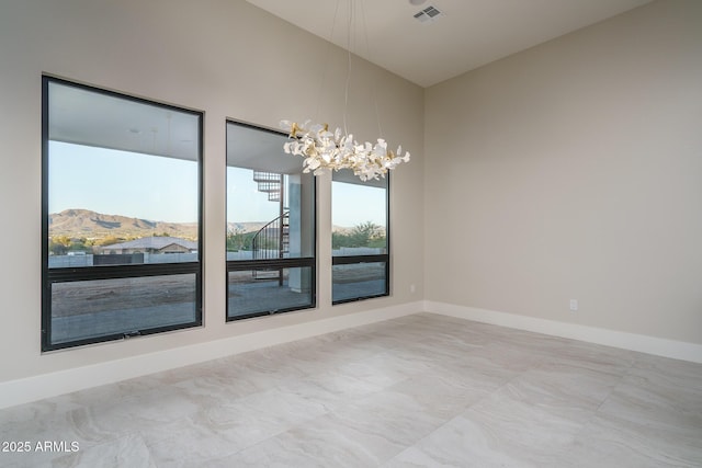 spare room with an inviting chandelier and a mountain view