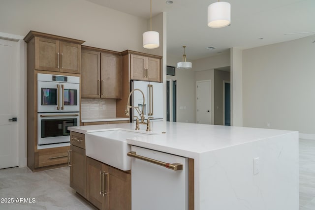 kitchen featuring a kitchen island with sink, sink, white appliances, and decorative light fixtures