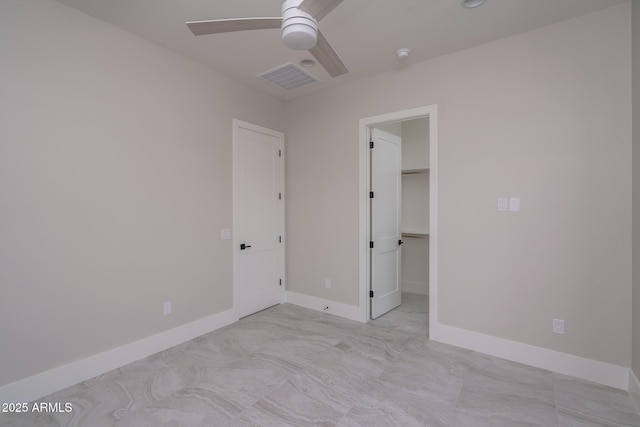 unfurnished bedroom featuring ceiling fan, a walk in closet, and a closet