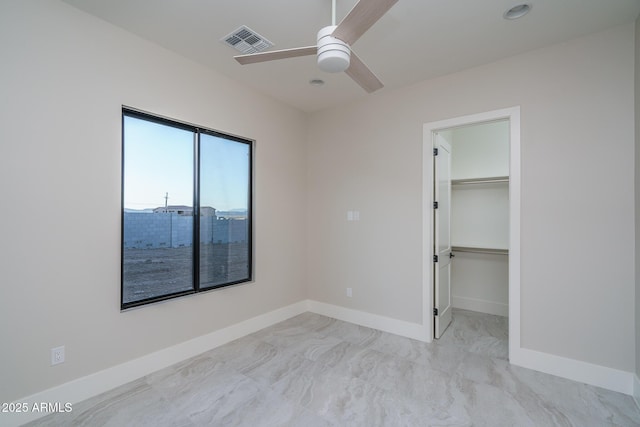 unfurnished bedroom with ceiling fan, a walk in closet, and a closet