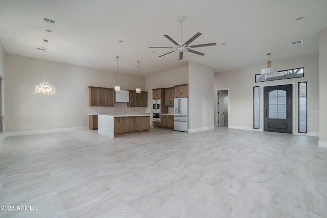 kitchen with pendant lighting, a towering ceiling, high end white fridge, and a center island