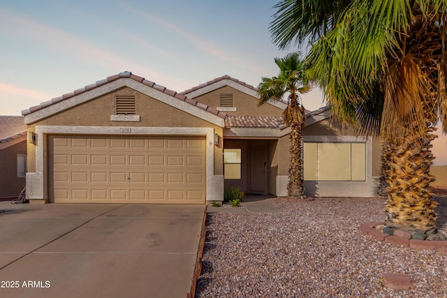 view of front of house with driveway, an attached garage, a tile roof, and stucco siding