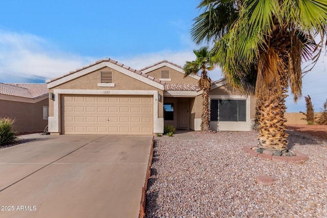 view of front facade featuring a garage, concrete driveway, a tile roof, and stucco siding