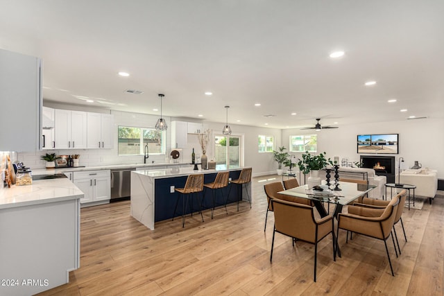 dining room featuring a wealth of natural light, light hardwood / wood-style floors, ceiling fan, and sink