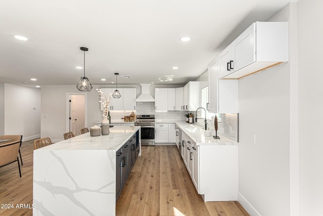 kitchen with custom exhaust hood, stainless steel range, decorative light fixtures, white cabinets, and a kitchen island