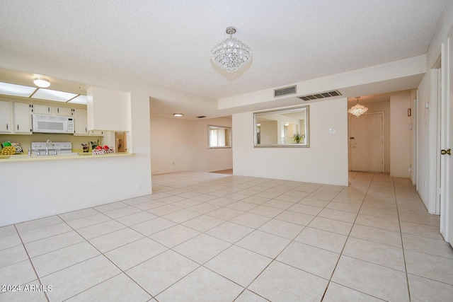 unfurnished living room with light tile patterned flooring, a chandelier, and a textured ceiling