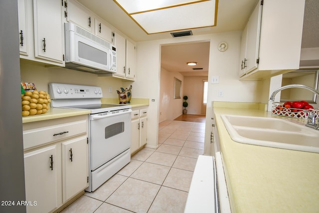 kitchen featuring sink, white appliances, light tile patterned floors, and white cabinets