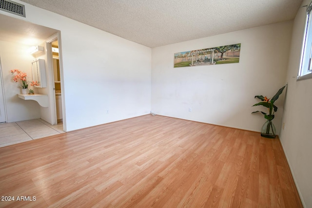 spare room featuring light hardwood / wood-style floors and a textured ceiling