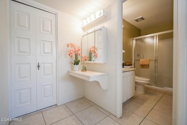 bathroom featuring a shower with door, tile patterned floors, and toilet