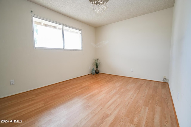 unfurnished room with light hardwood / wood-style floors and a textured ceiling