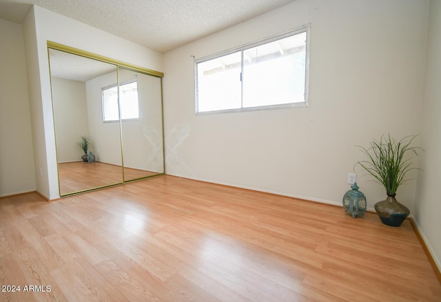 unfurnished bedroom featuring a closet, light hardwood / wood-style flooring, and a textured ceiling