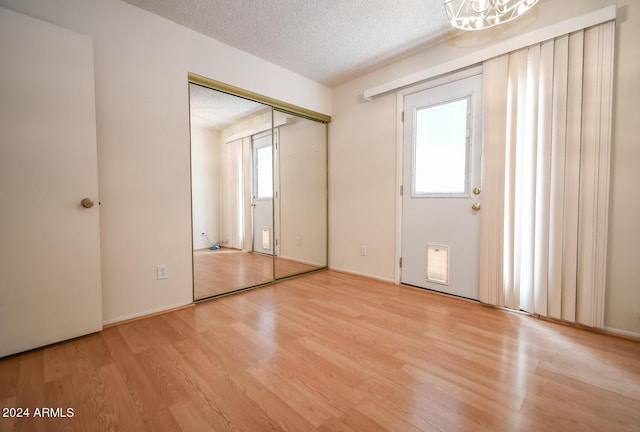 unfurnished bedroom featuring a textured ceiling, multiple windows, and light wood-type flooring