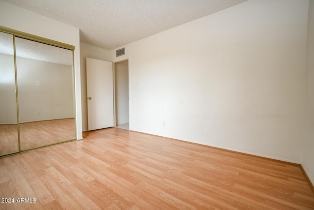 unfurnished bedroom featuring a closet, light hardwood / wood-style floors, and a textured ceiling