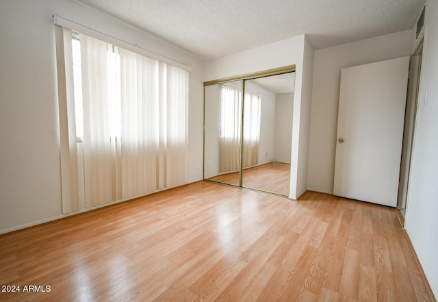 unfurnished bedroom featuring a closet, a textured ceiling, and light wood-type flooring