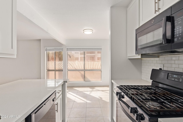 kitchen featuring tasteful backsplash, black appliances, light tile patterned flooring, and white cabinets