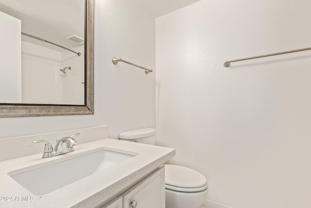 bathroom with vanity, a shower, and toilet