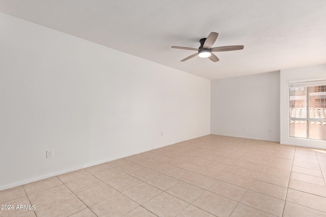 tiled empty room featuring ceiling fan