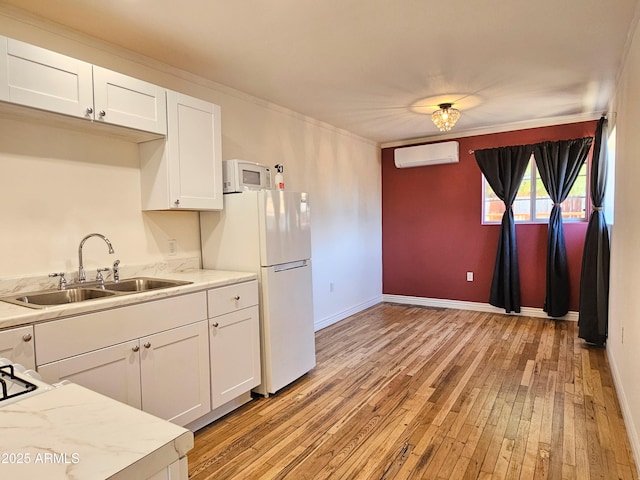 1374 S Naco Hwy, Bisbee, AZ 85603 - kitchen featuring a wall mounted AC, a sink, white appliances, light wood-style floors, and white cabinetry