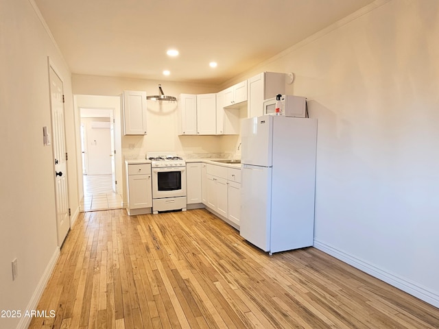 1374 S Naco Hwy, Bisbee, AZ 85603 - kitchen featuring white appliances, light wood-style flooring, baseboards, light countertops, and white cabinets