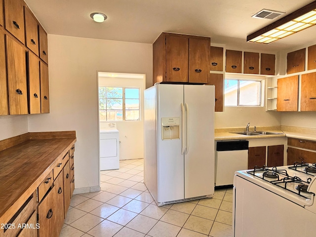 1374 S Naco Hwy, Bisbee, AZ 85603 - kitchen with white appliances, washer / dryer, a sink, brown cabinetry, and light tile patterned flooring