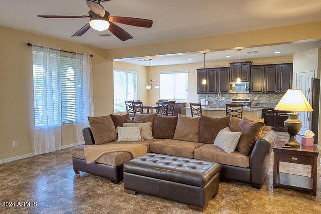 living room with ceiling fan with notable chandelier and sink