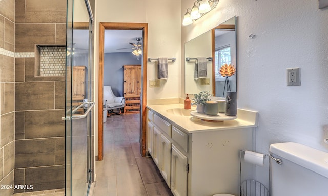 bathroom with vanity, ceiling fan, wood-type flooring, toilet, and a shower with shower door