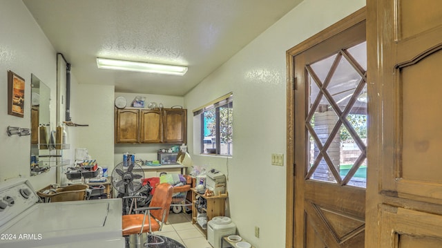 laundry area featuring cabinets, light tile patterned flooring, washer / dryer, and a textured ceiling