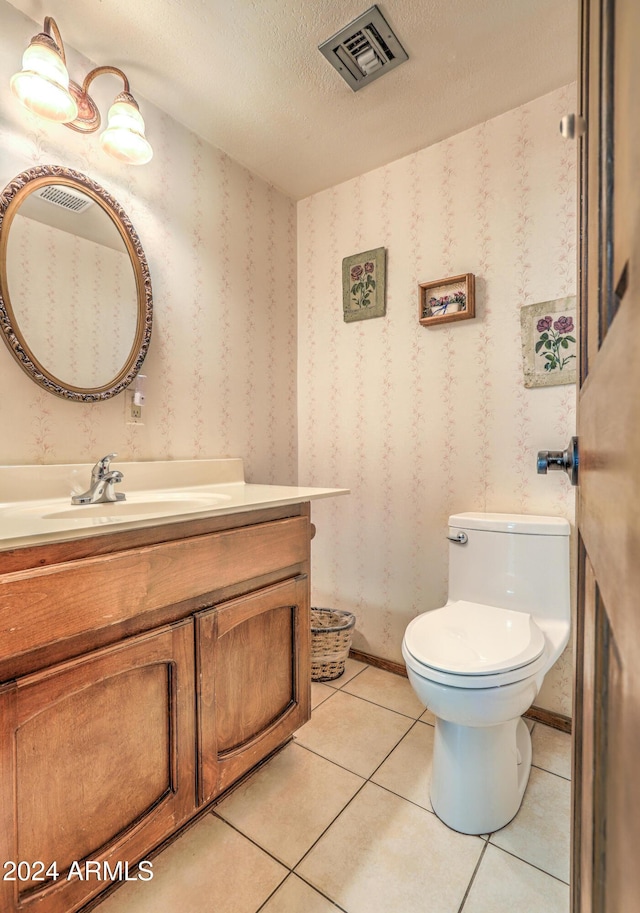 bathroom with tile patterned flooring, vanity, a textured ceiling, and toilet