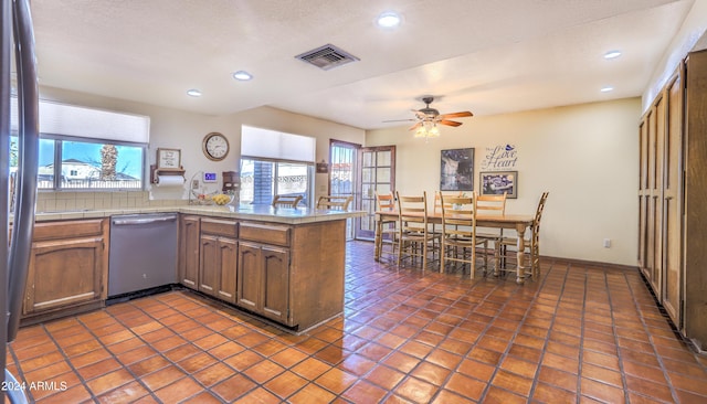 kitchen featuring kitchen peninsula, ceiling fan, dark tile patterned floors, and stainless steel dishwasher