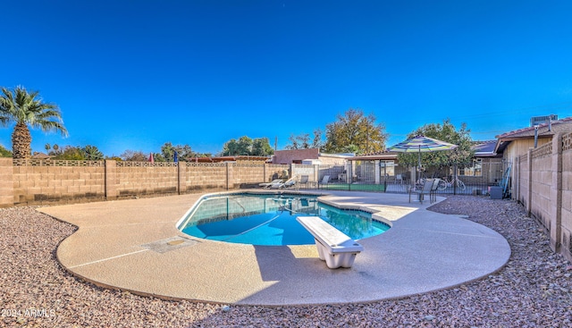 view of pool with a diving board and a patio area