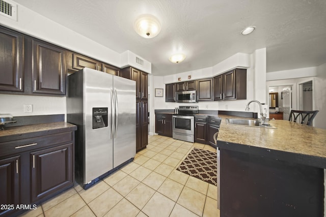 13160 W Windsor Ave, Goodyear, AZ 85395 - kitchen with stainless steel appliances, dark brown cabinets, light tile patterned floors, a peninsula, and dark countertops