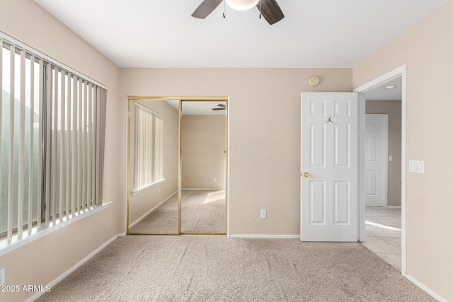 unfurnished bedroom featuring ceiling fan, light colored carpet, and a closet