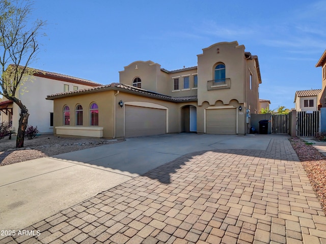 view of front of property with decorative driveway, a gate, a tile roof, and stucco siding