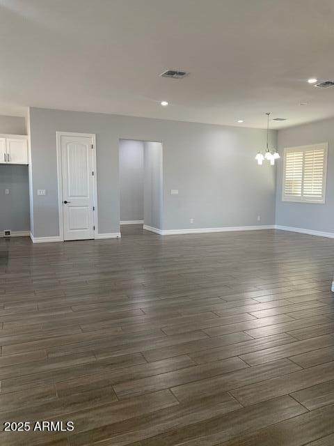 2319 N 192nd Ave, Buckeye, AZ 85396 - unfurnished living room featuring baseboards, visible vents, dark wood-style flooring, and a chandelier