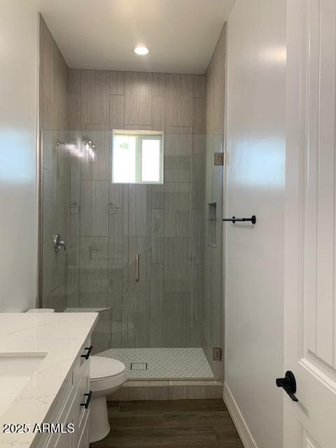 2319 N 192nd Ave, Buckeye, AZ 85396 - bathroom with wood finished floors, a stall shower, toilet, and vanity