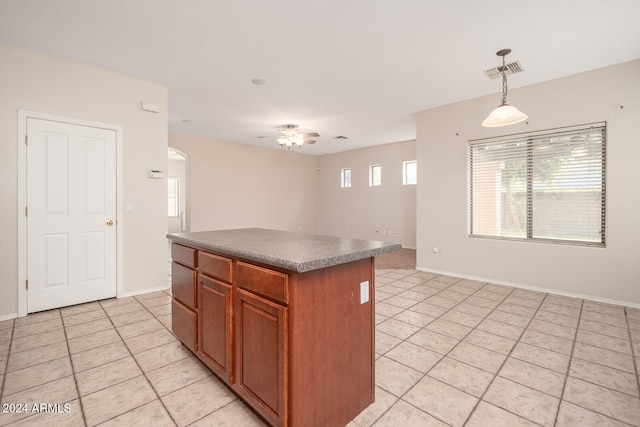 kitchen with decorative light fixtures, a center island, light tile patterned floors, and ceiling fan