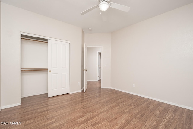 unfurnished bedroom with ceiling fan, a closet, and wood-type flooring