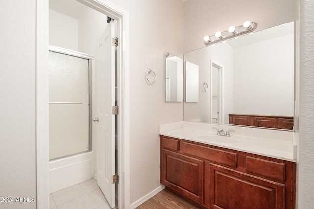 bathroom featuring tile patterned floors, vanity, and enclosed tub / shower combo